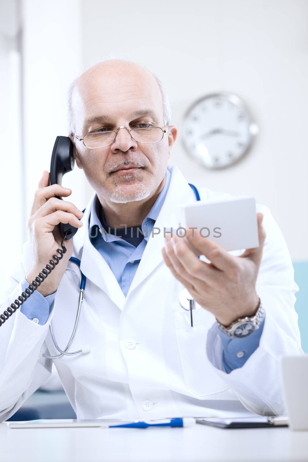 Doctor talking on the phone and looking at medicine's box.