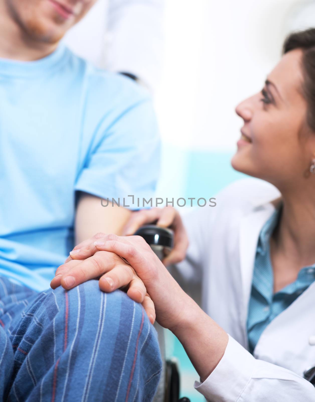 Young female doctor comforting a young patient on wheelchair.