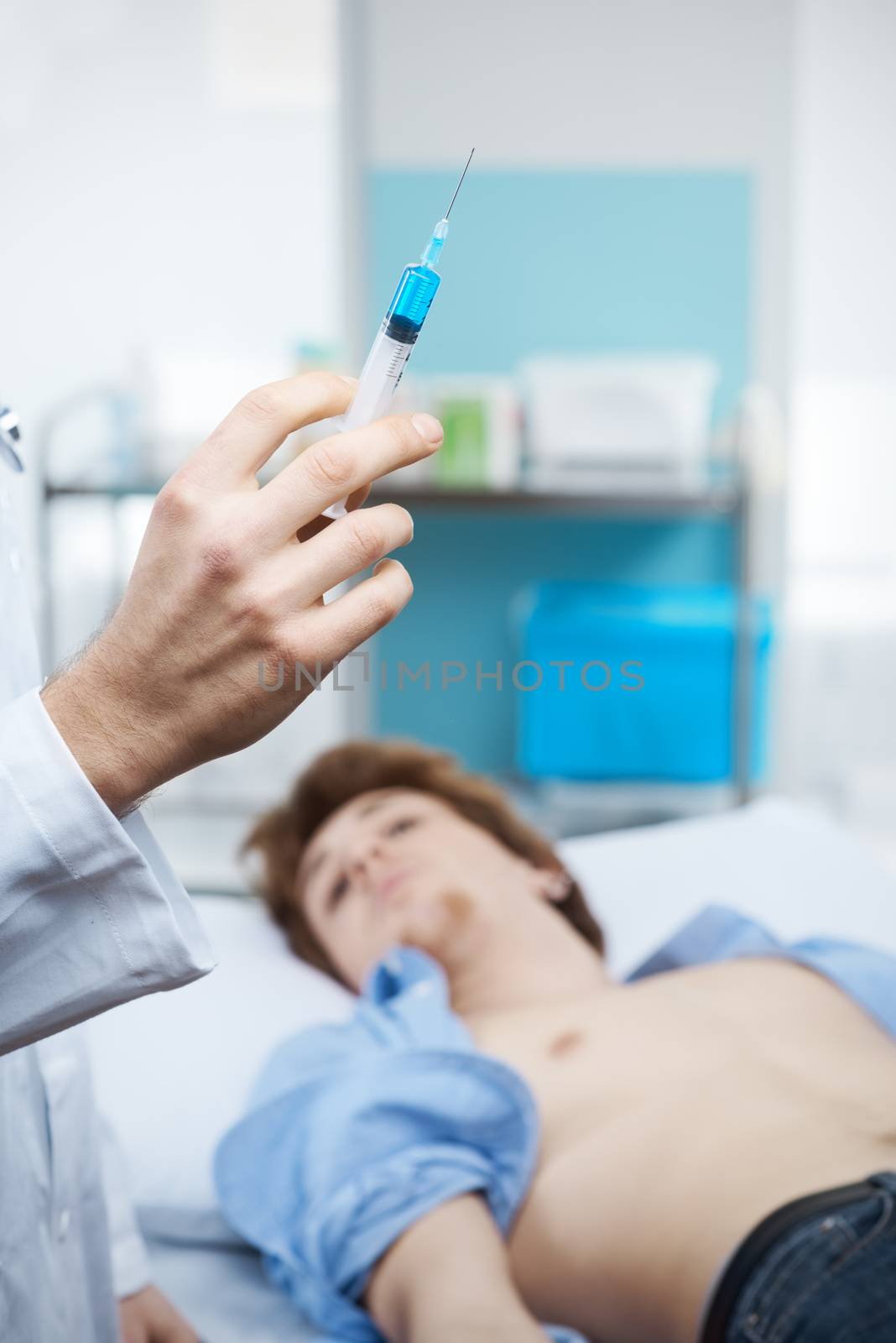 Doctor preparing a syringe for an injection with patient on the background.