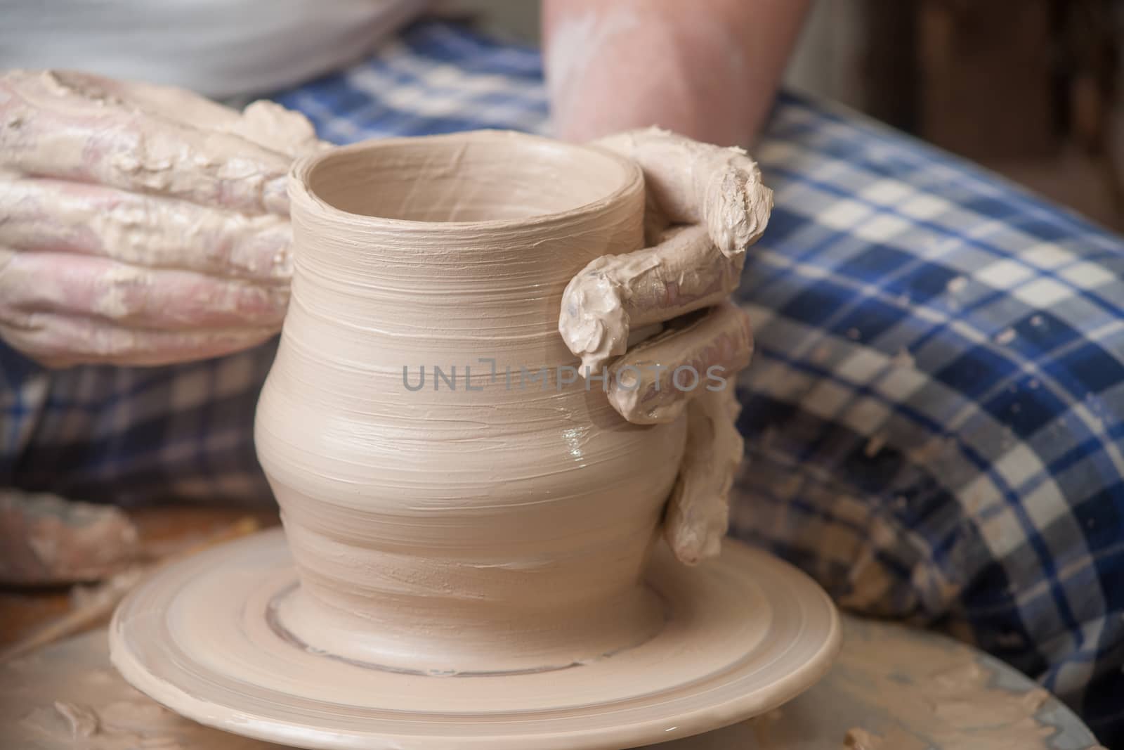 Hands of a potter, creating an earthen jar on the circle