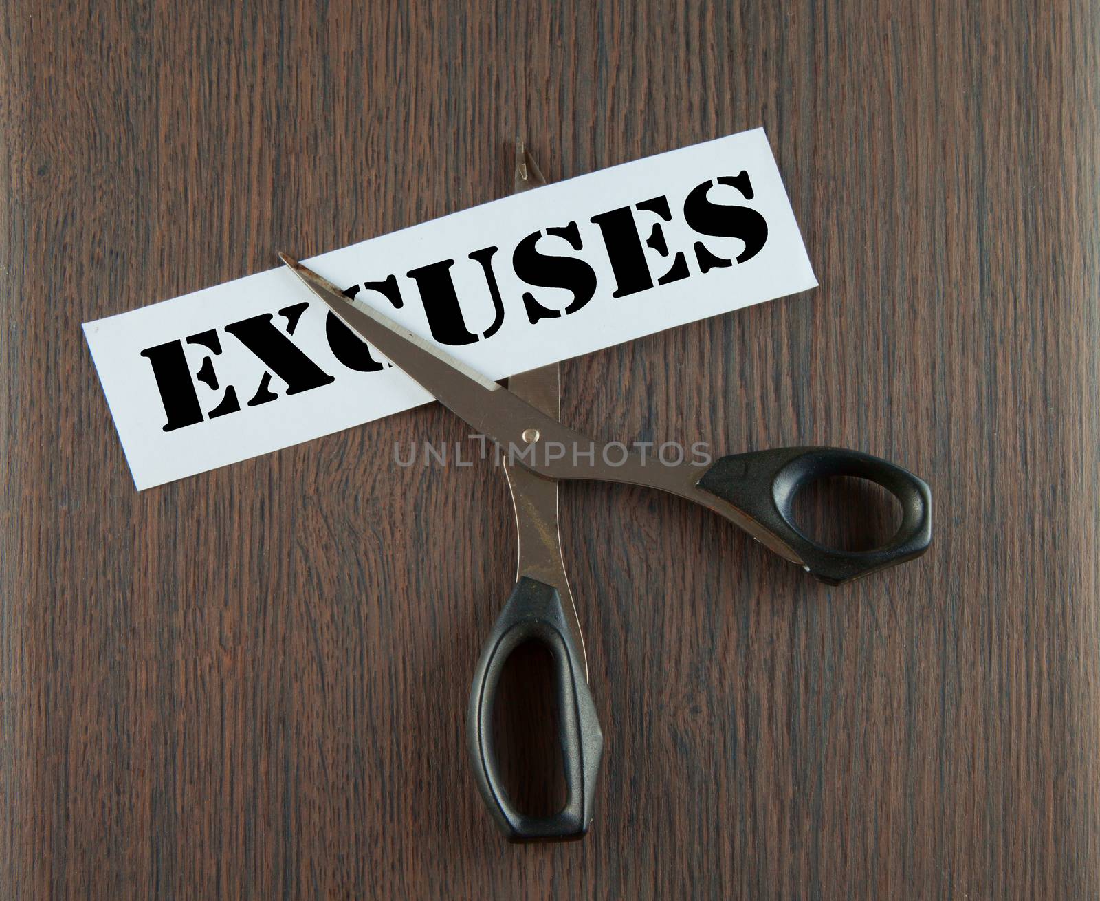 Scissors cutting the word "Crisis" written on a paper strip, over wooden background