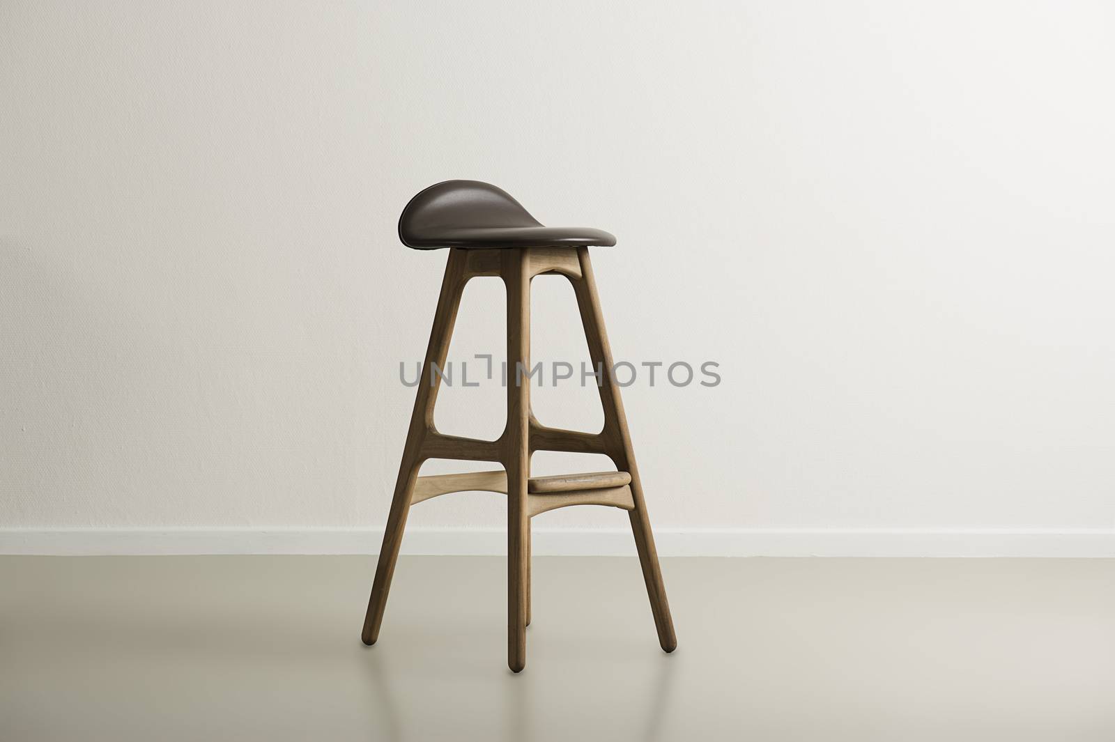 Wooden bar stool with a molded leather seat standing centered in a minimalist empty room with a white wall and copyspace, horizontal format