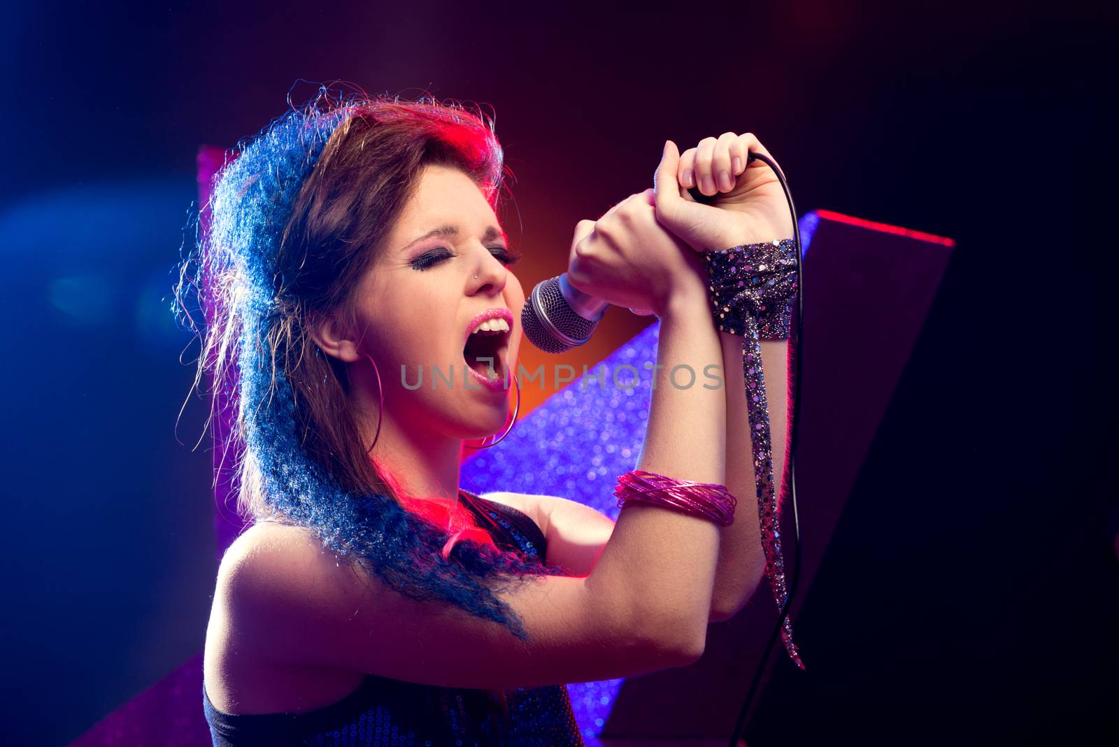 Young pop star girl singing on stage close up.