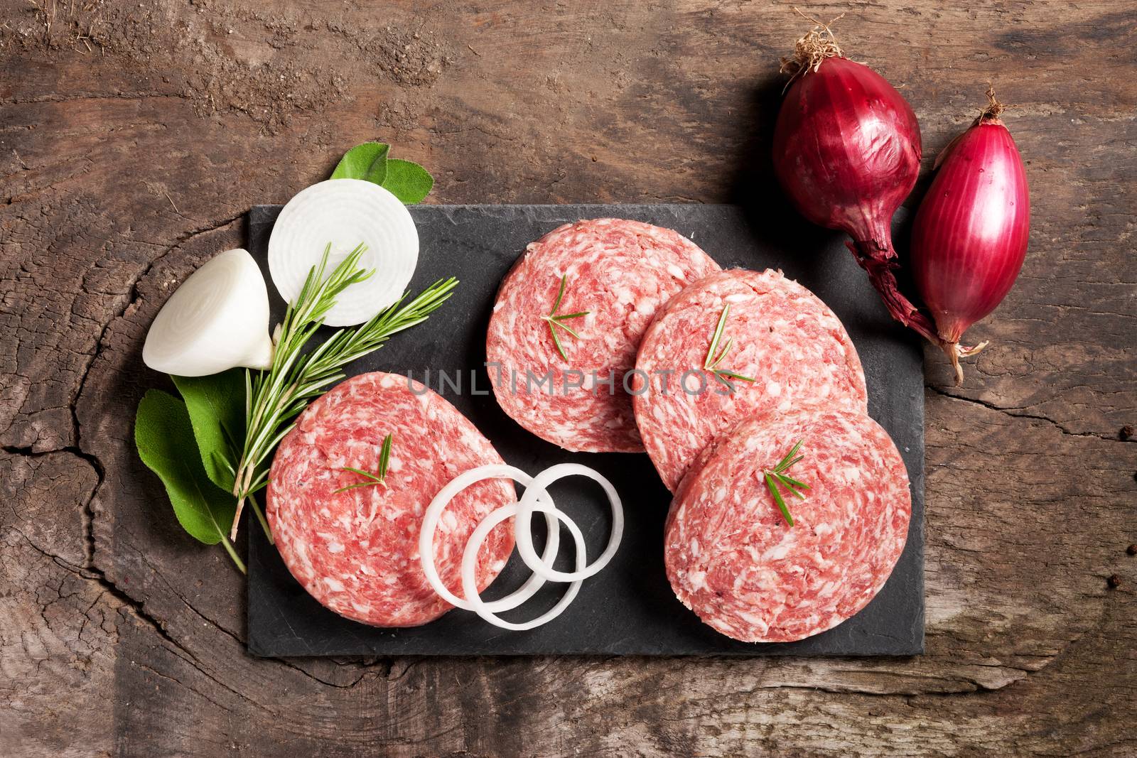 Slices of fresh salami on board with onions and spices.
