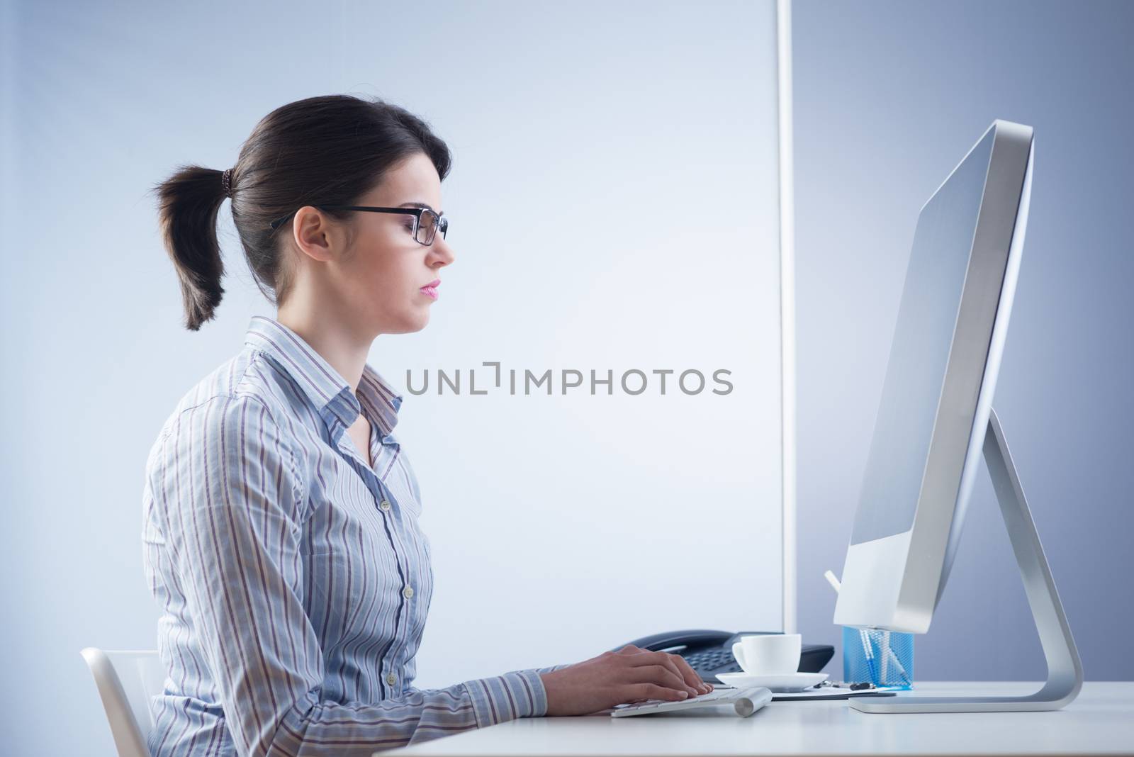 Serious confident businesswoman at desk working at computer.