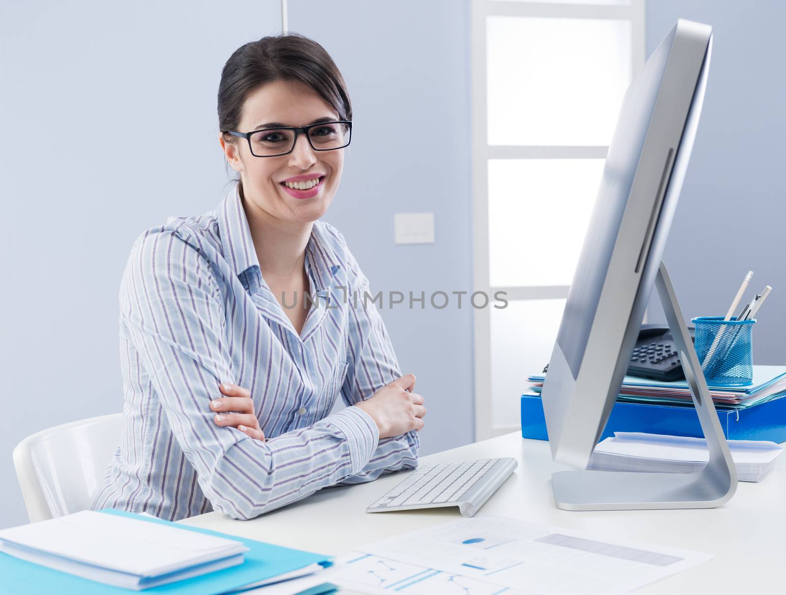 Attractive young businesswoman smiling confidently at her desk.