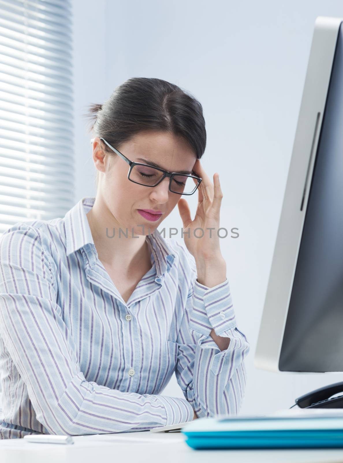 Tired office worker with headache touching her temples.