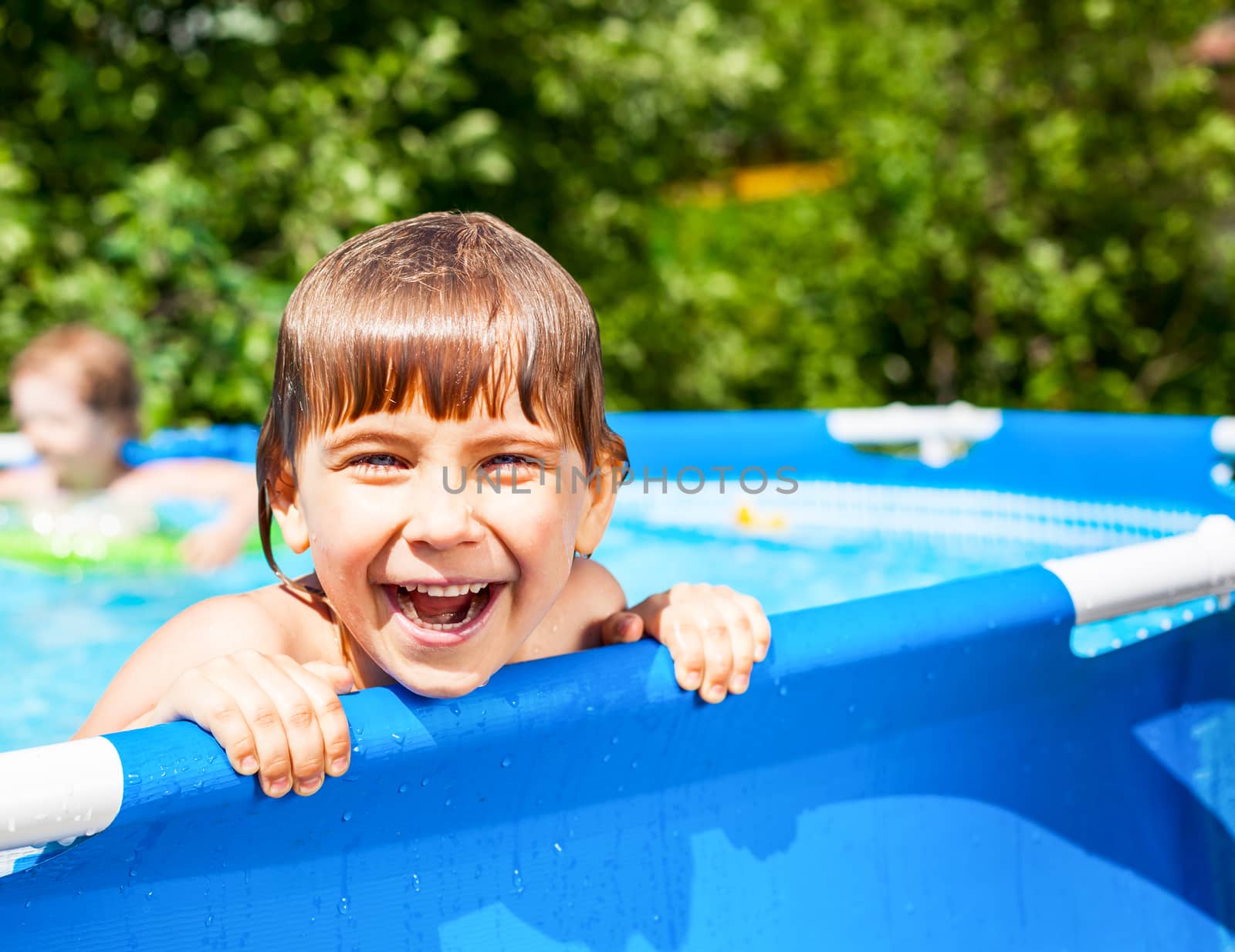 Little girl palying in a swimming pool at a summer garden