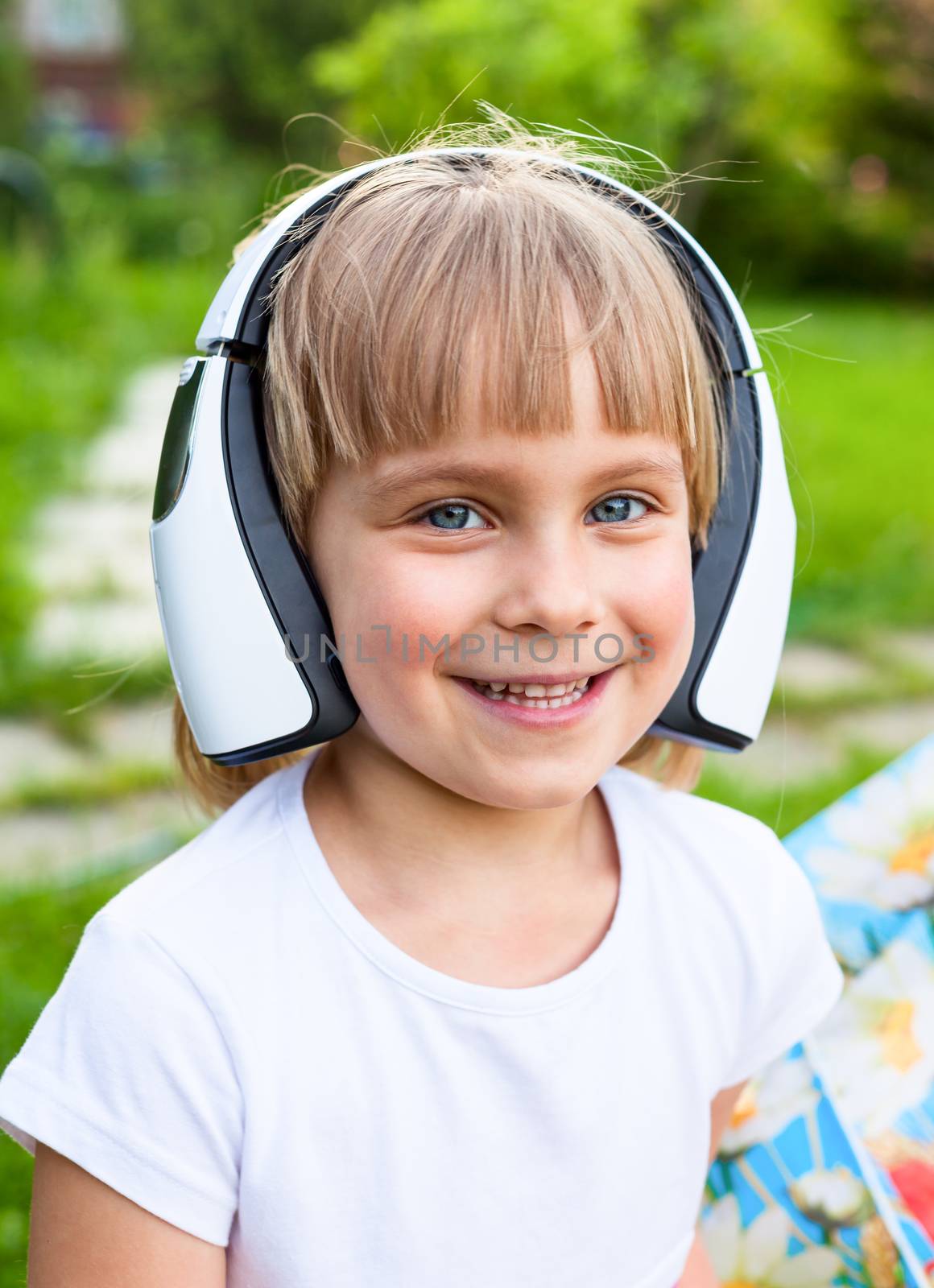 Portrait of cute 5 years girl wearing wireless headphones outdoors