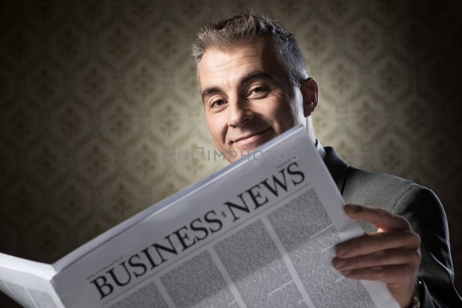 Handsome businessman reading news against vintage wallpaper background.