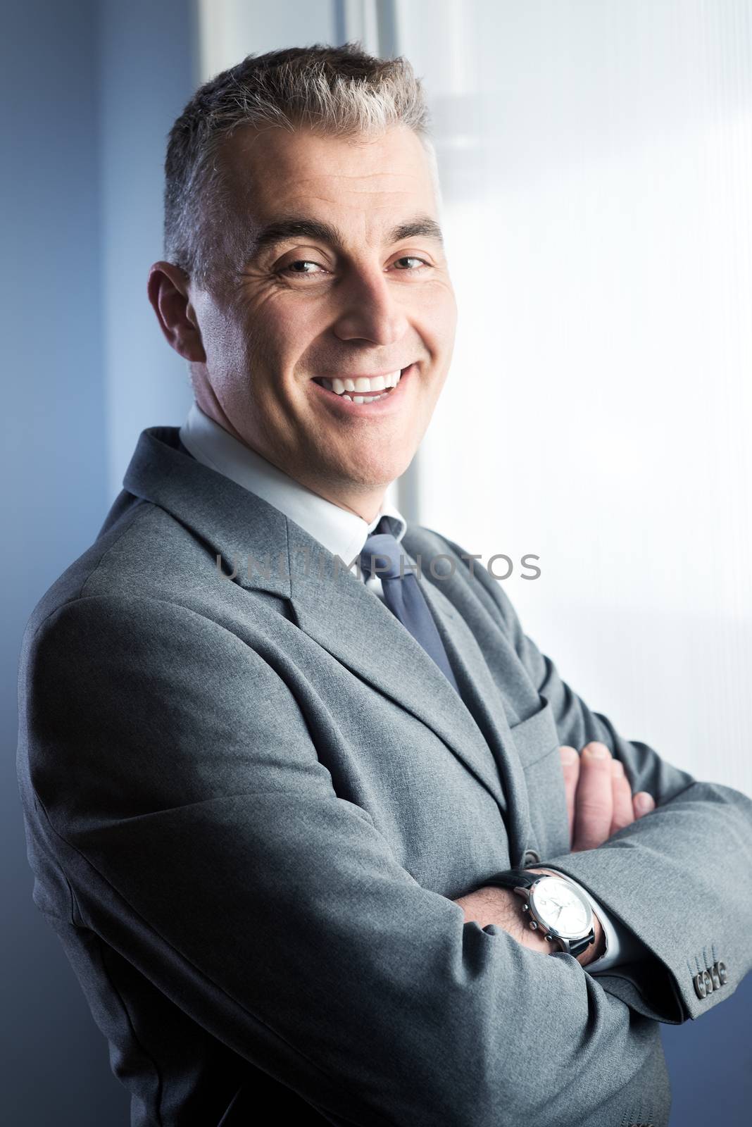 Confident businessman with arms crossed smiling at camera.