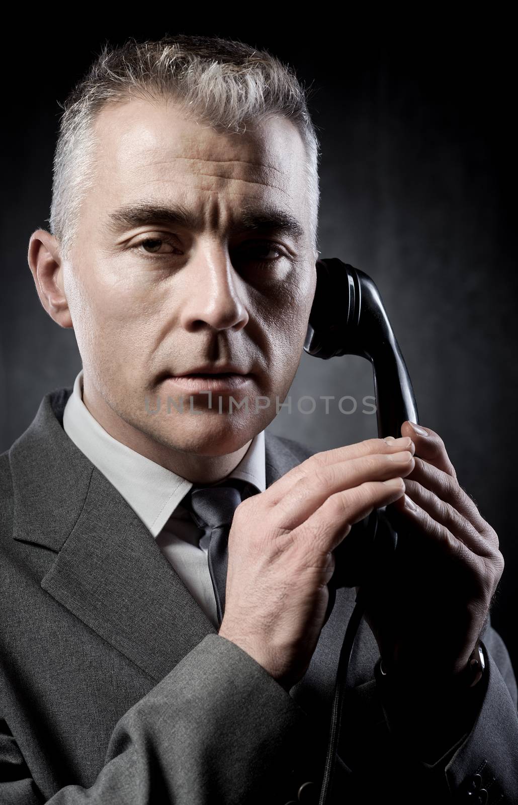 Handsome man holding a vintage phone receiver on dark background.