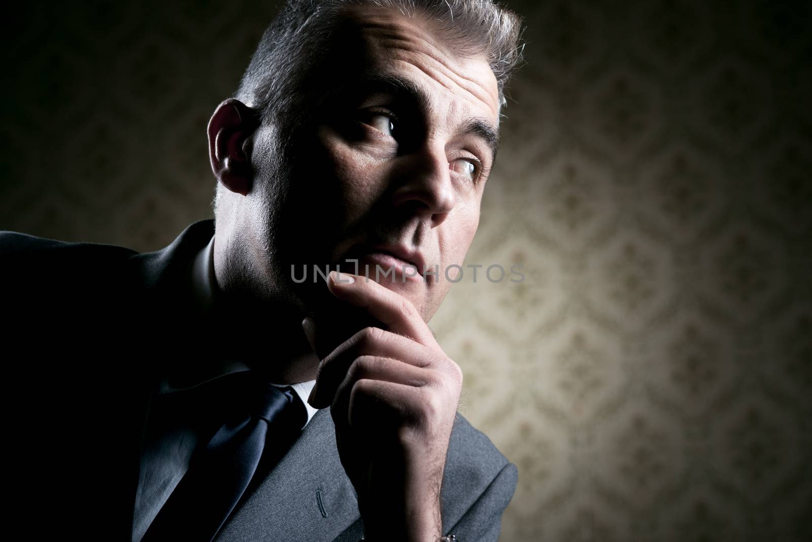 Vintage businessman with pensive expression on retro wallpaper background.