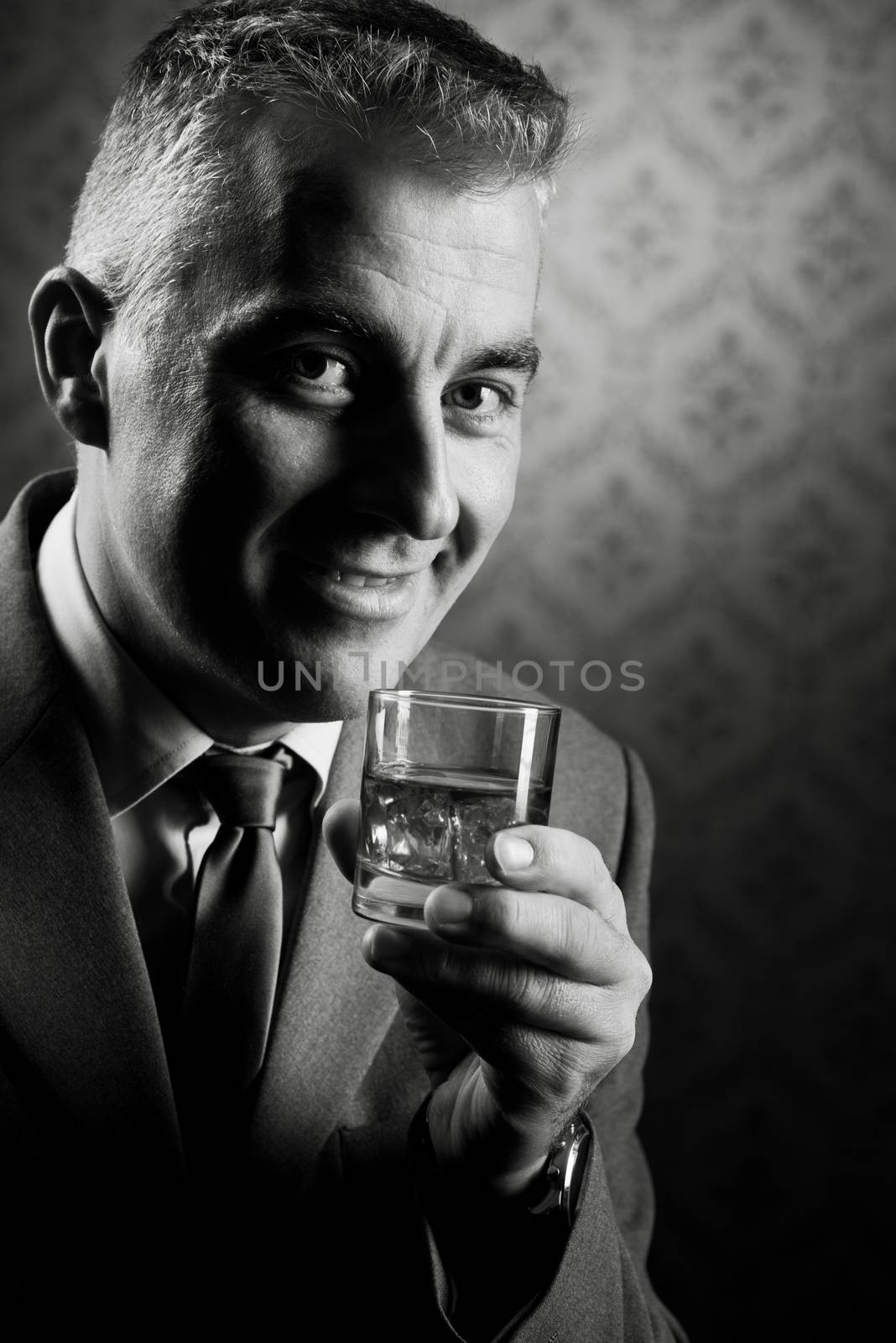 Vintage businessman holding a glass of whisky by stokkete