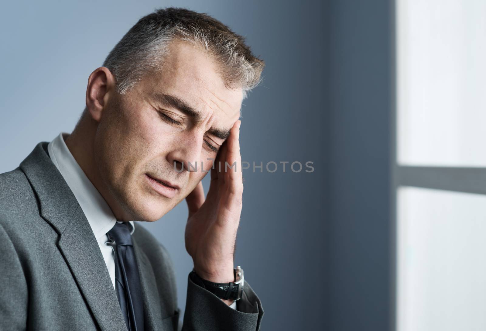 Mature businessman with headache touching his temple