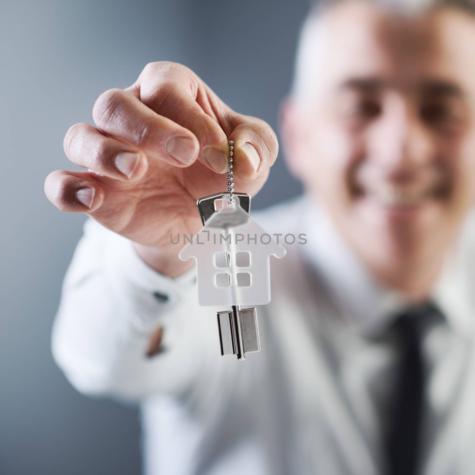 Real estate agent holding out house keys by stokkete