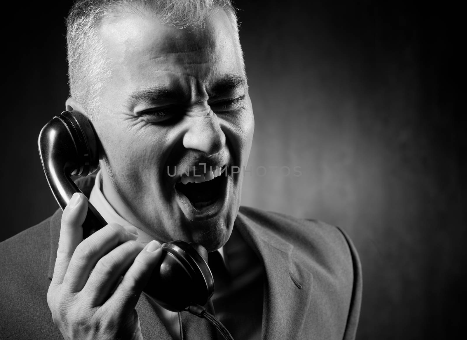 Handsome man holding a vintage phone receiver on dark background.