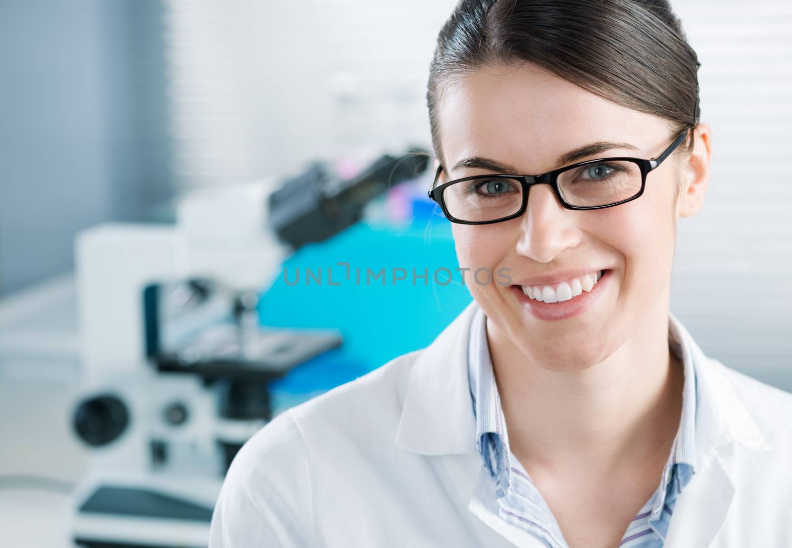 Young female researcher in the chemistry lab with equipment on background.