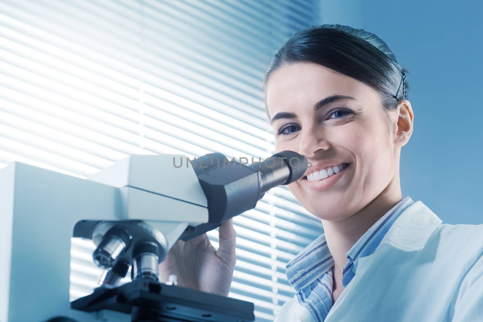 Female researcher working with microscope by stokkete