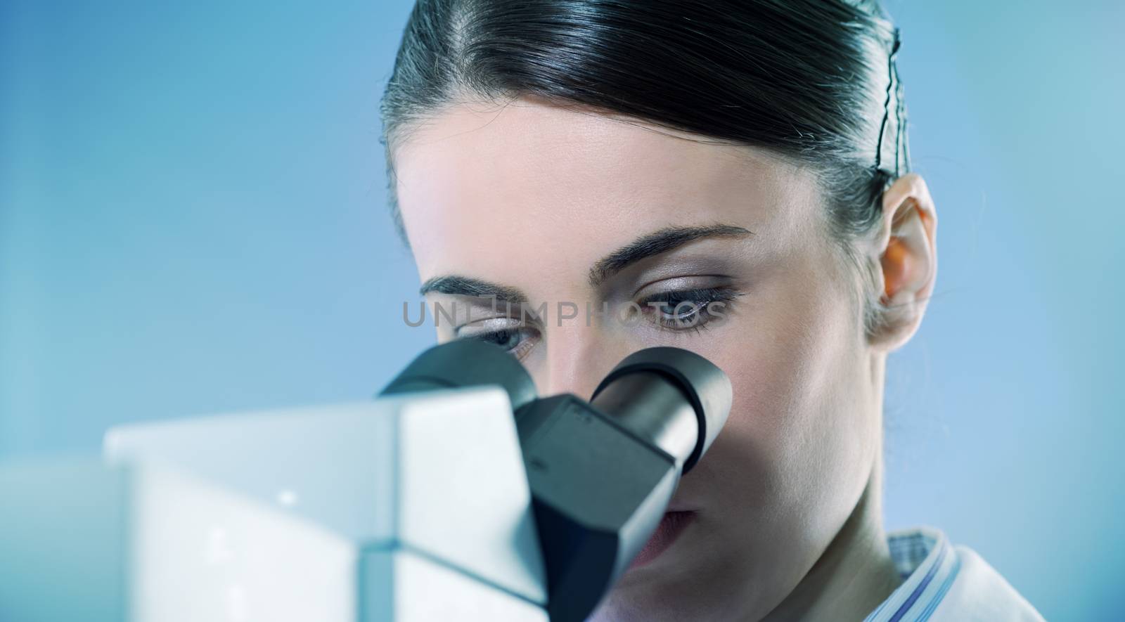 Young female researcher using microscope in the laboratory close up.