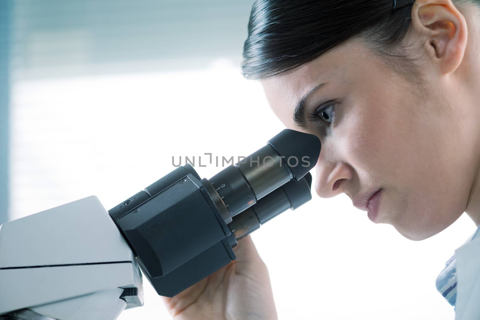 Female researcher using microscope close up by stokkete