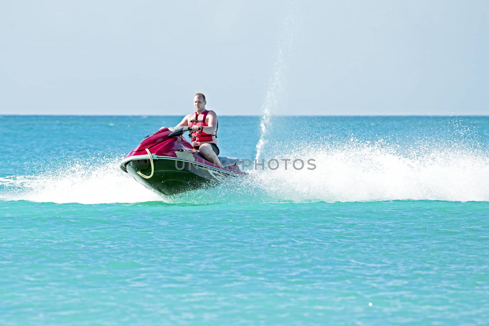 Young guy cruising on a jet ski on the caribbic sea