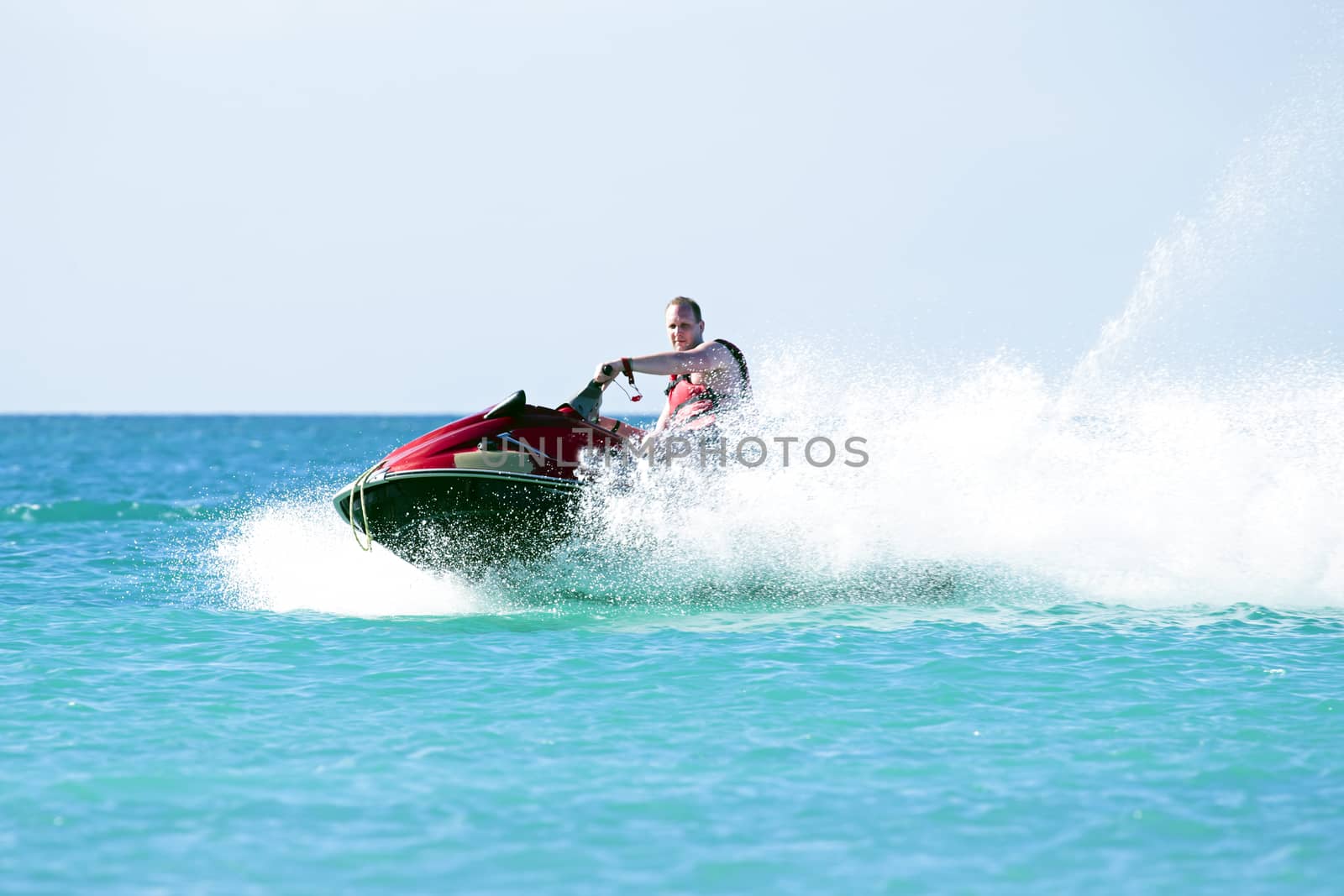 Young guy cruising on a jet ski on the caribbic sea