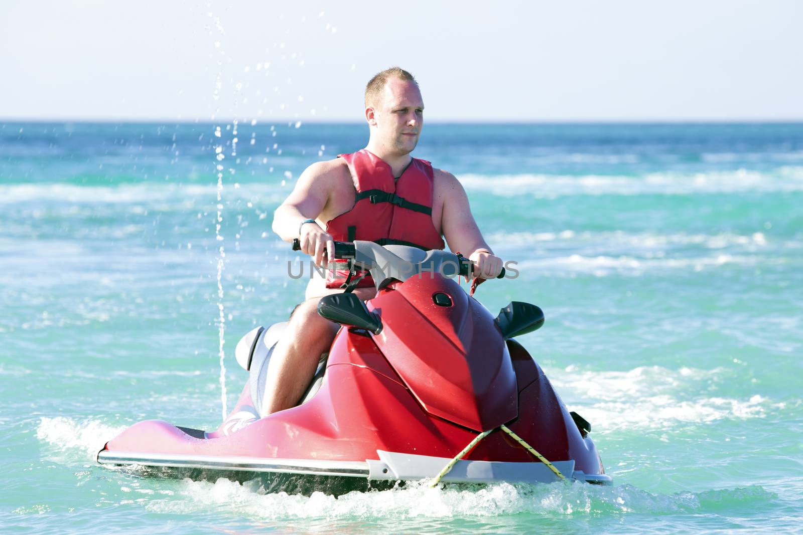 Young guy cruising on a jet ski on the caribbic sea