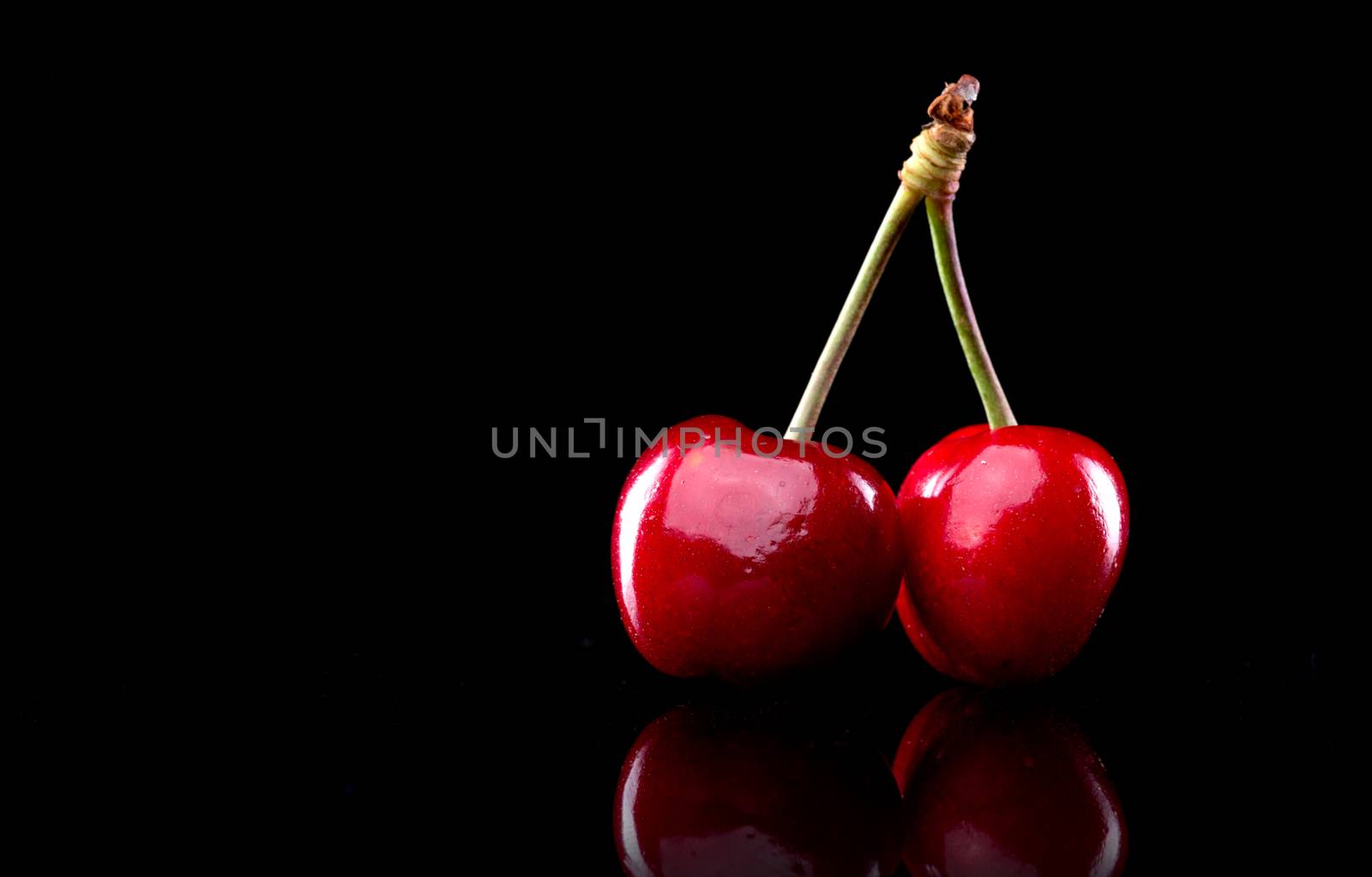 Ripe juicy cherries standing on black background.