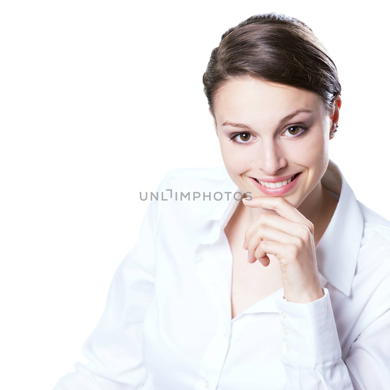 Confident young woman in white shirt with hand on chin smiling at camera.