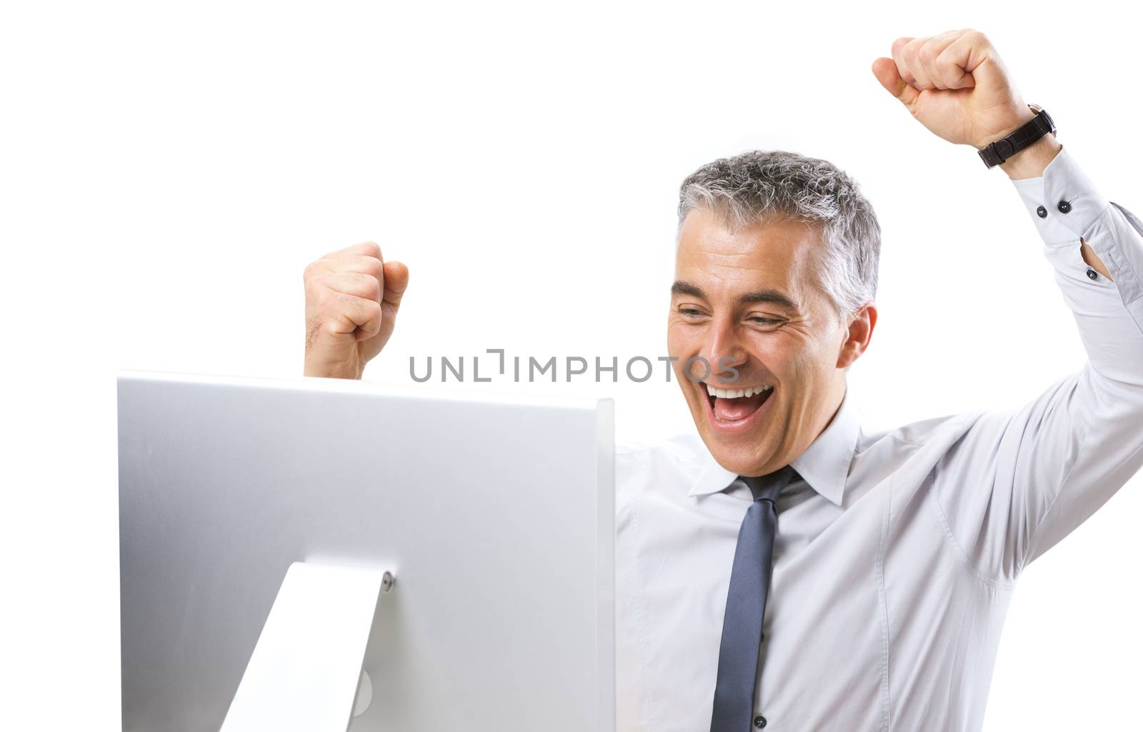 Mature businessman receiving good news on computer with fists raised.