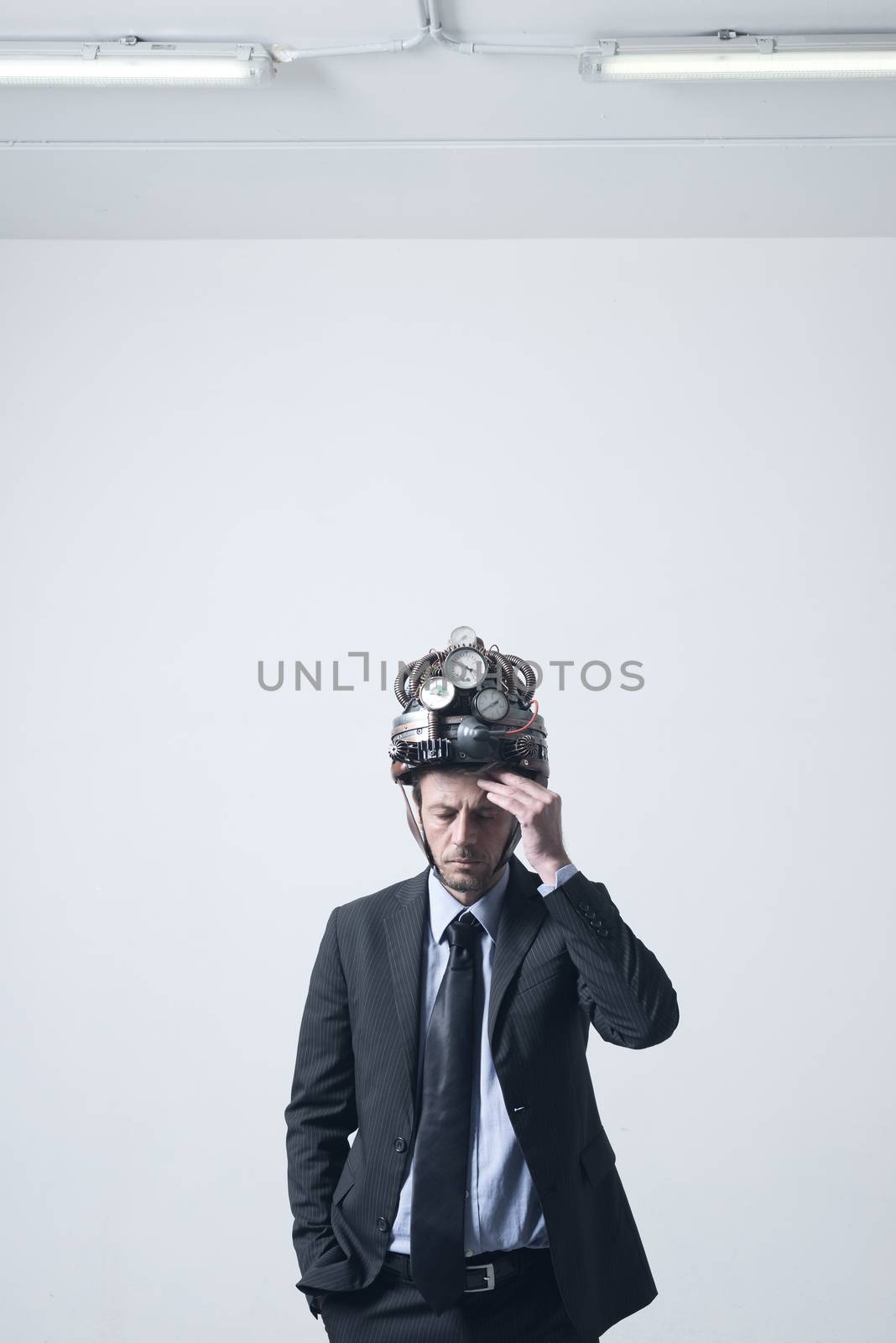 Tired pensive businessman touching his forehead weaaring futuristic helmet with gauges.