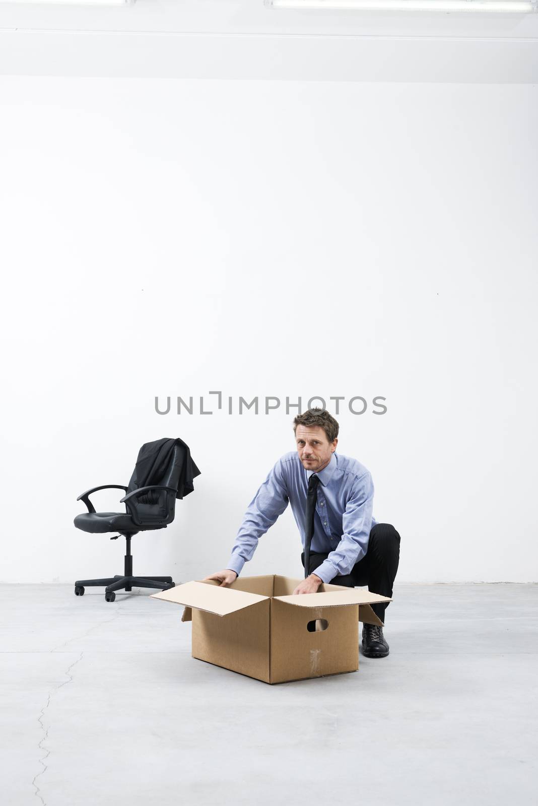 Businessman looking around and packing with cardboard box in an empty office.