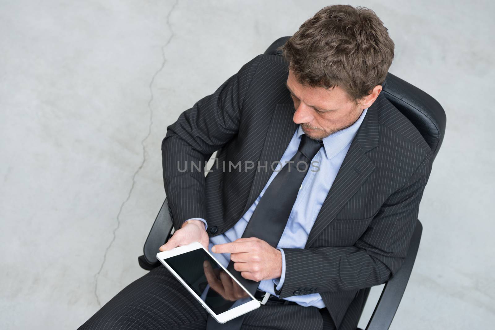 Businessman working with tablet on concrete floor background.