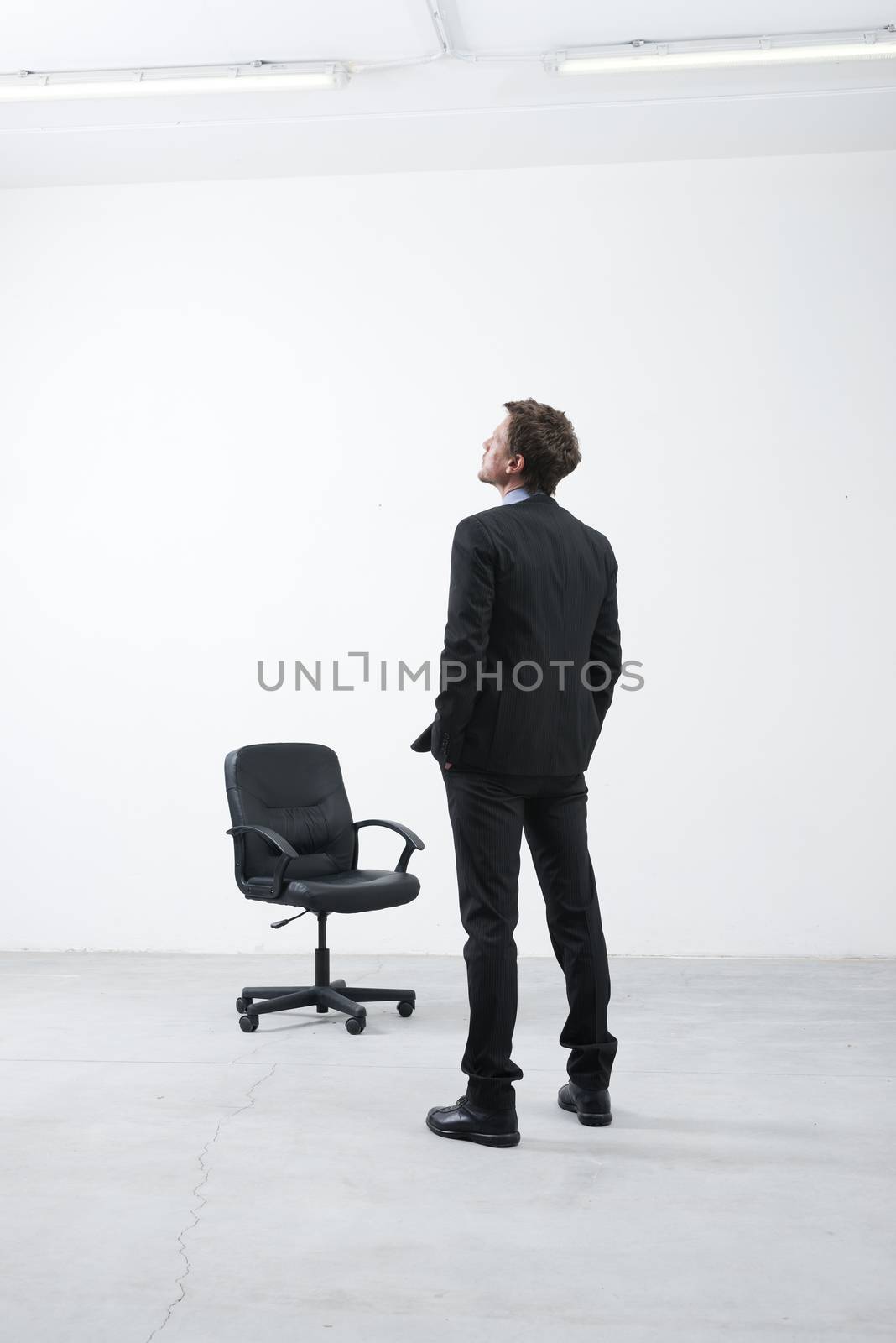 Smiling businessman standing in his new empty office with hands in pockets looking around.