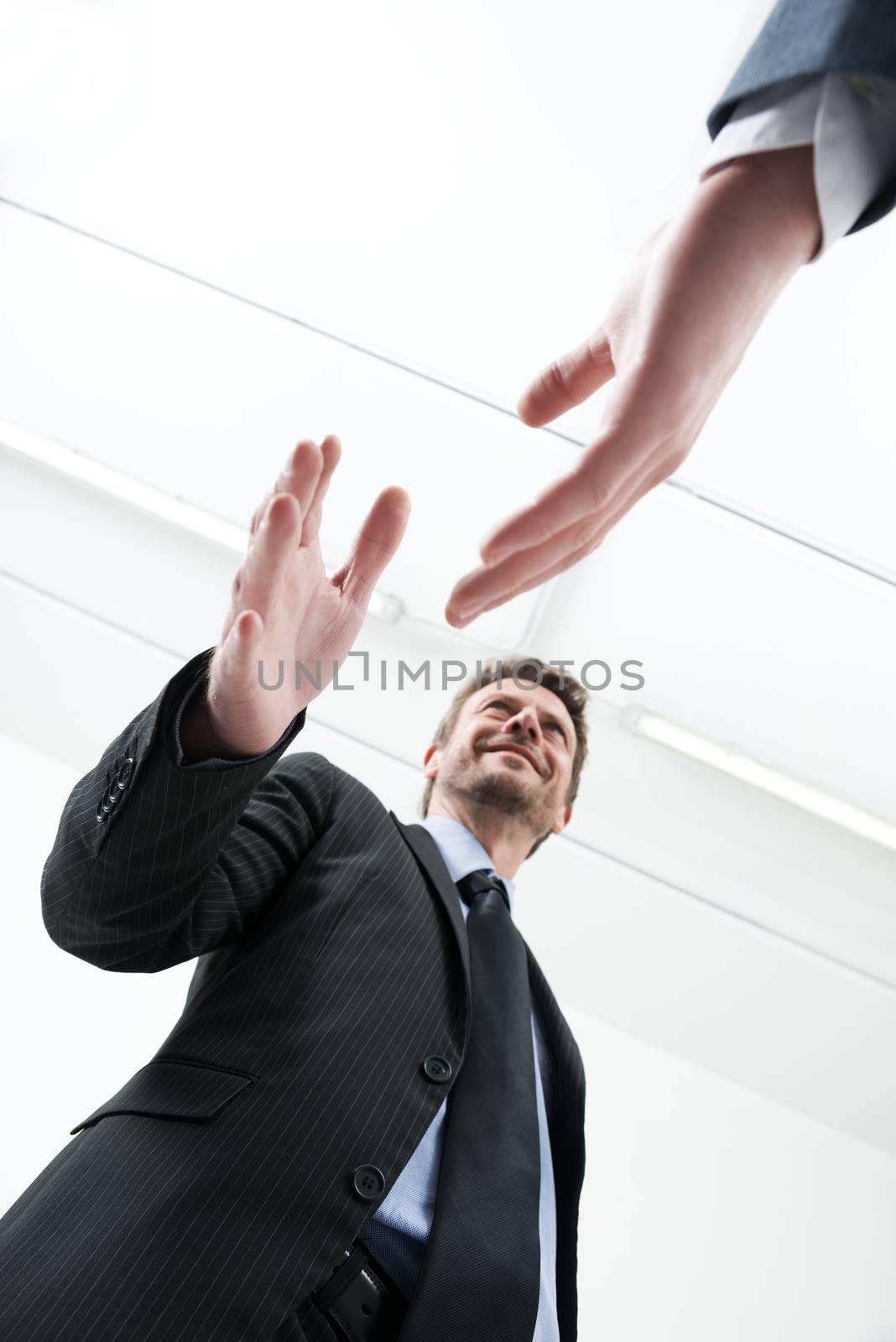 Confident young businessmen smiling and shaking hands bottom view.