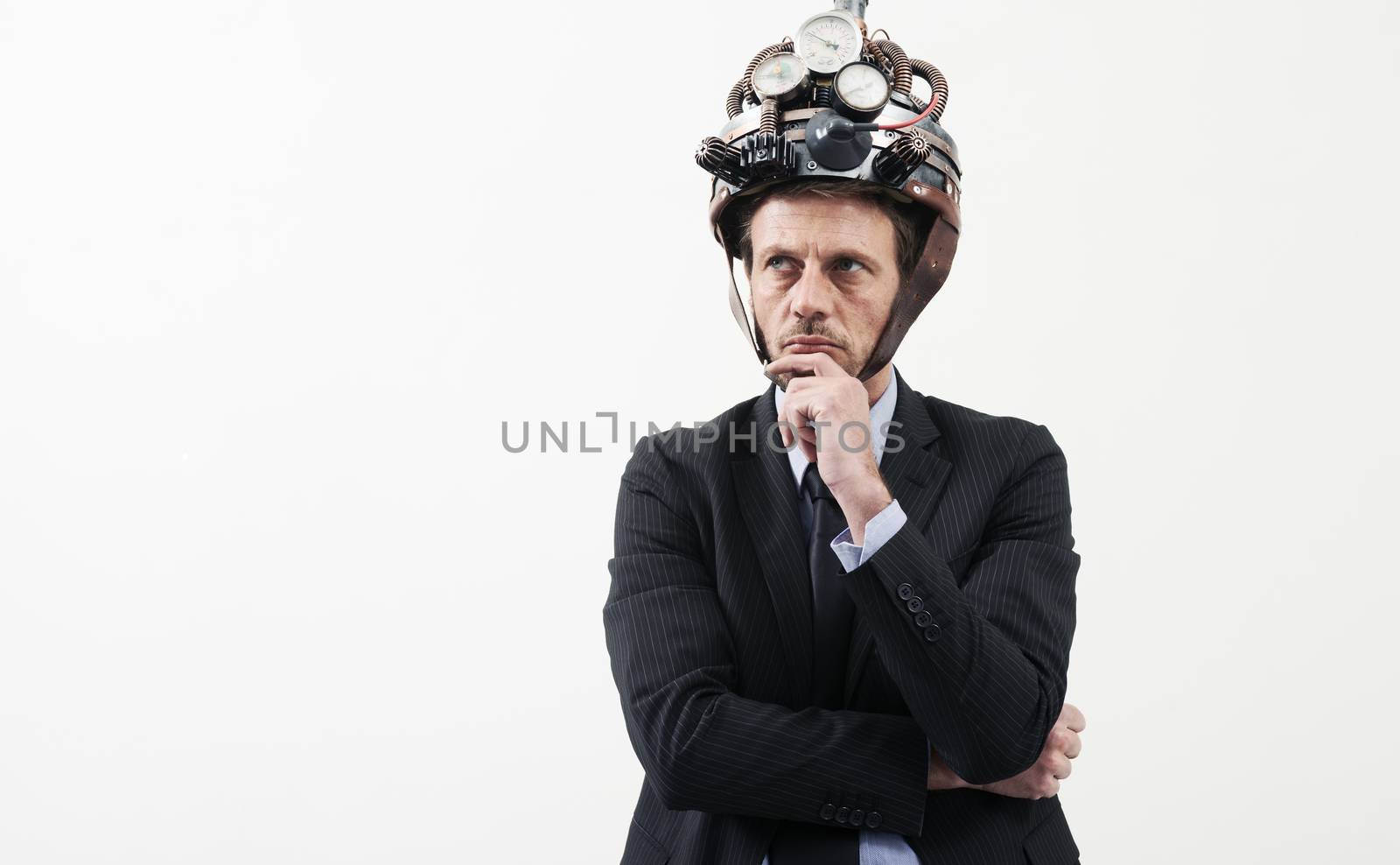 Confident businessman thinking with hand on chin wearing steampunk helmet on white background.