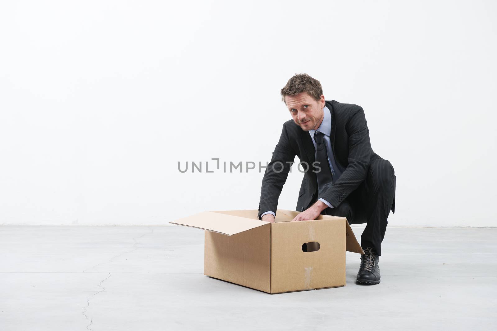 Businessman looking around and packing with cardboard box in an empty office.