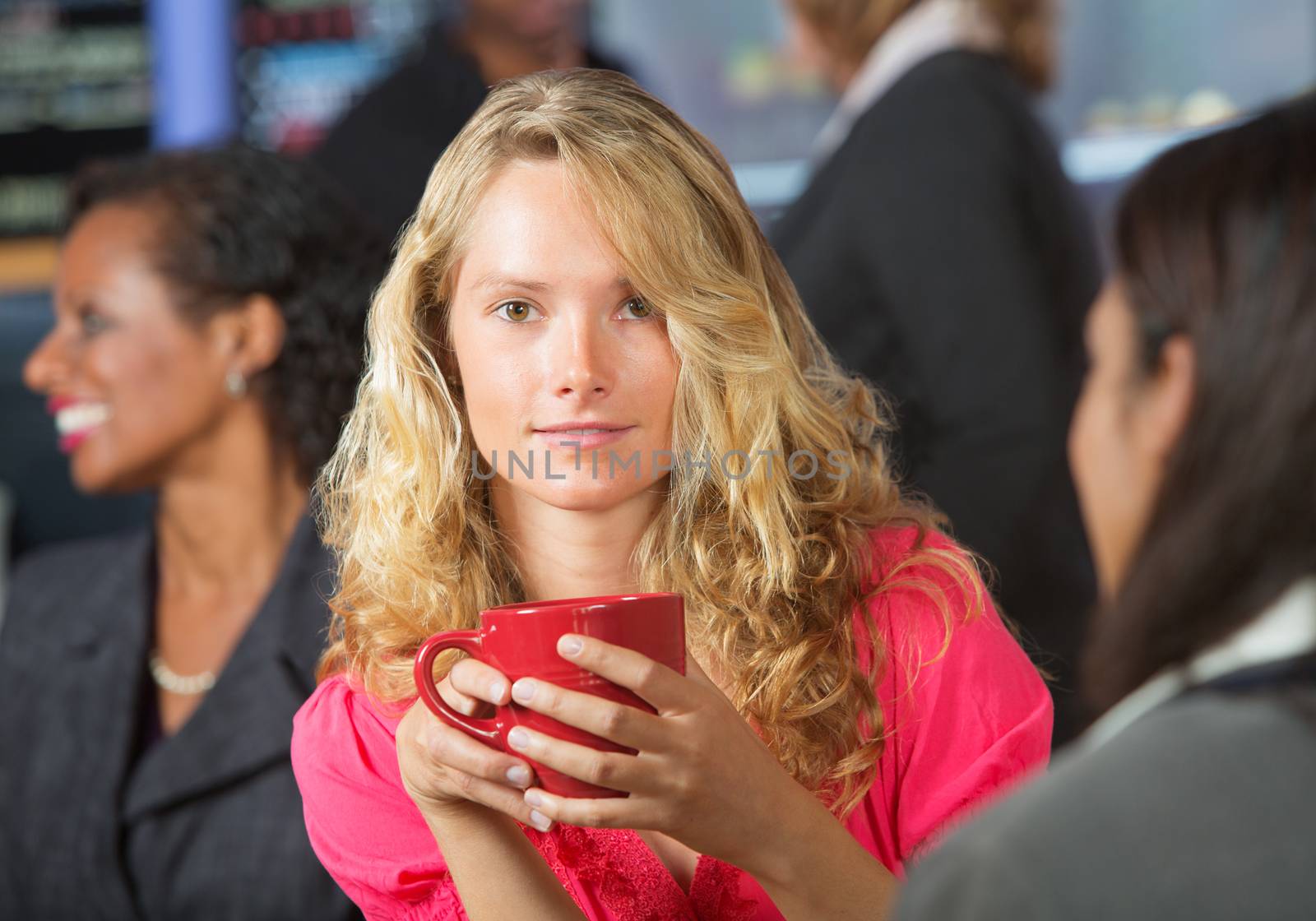Happy young blond woman holding red coffee mug