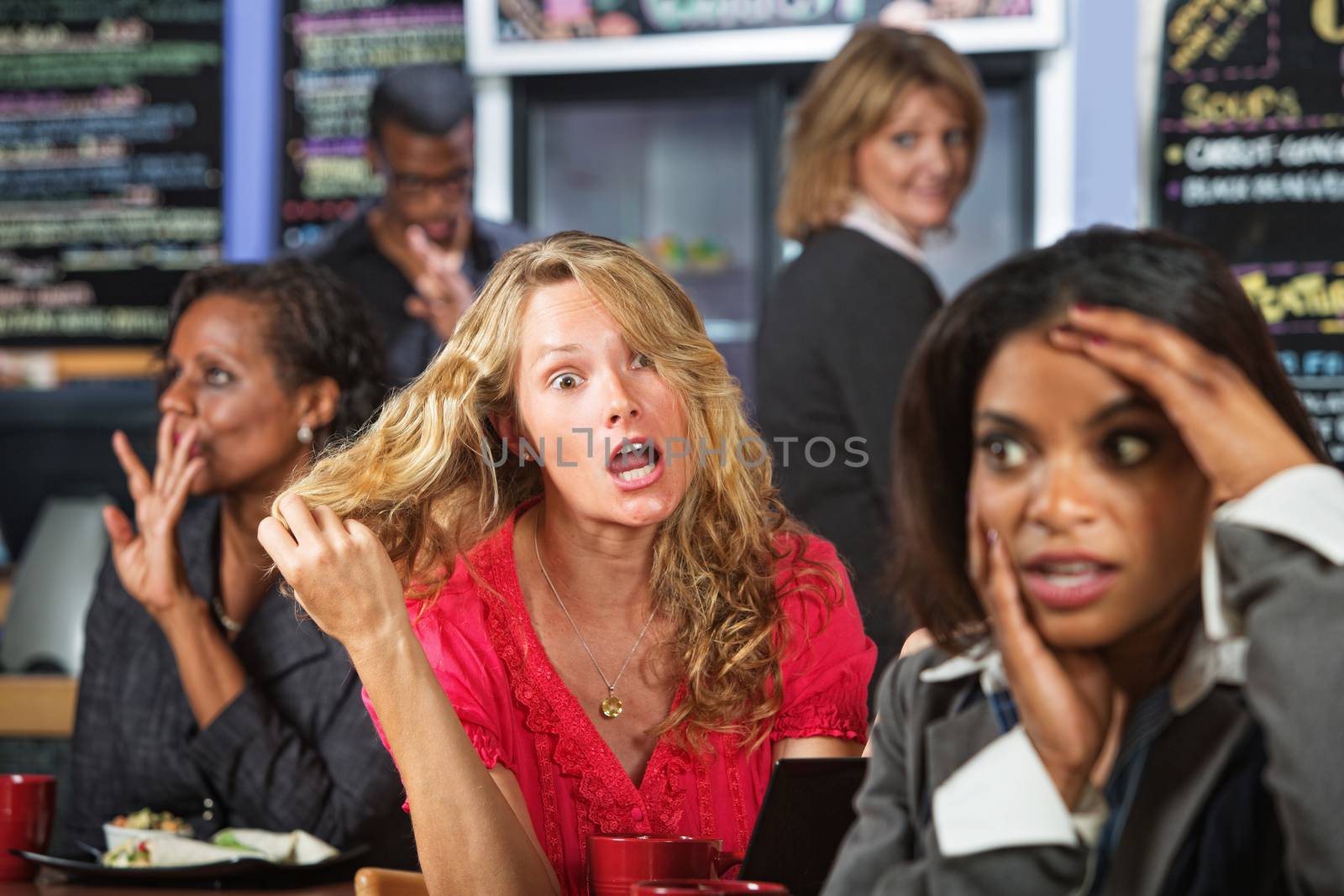 Emotional woman pulling hair in cafe with embarrassed friend