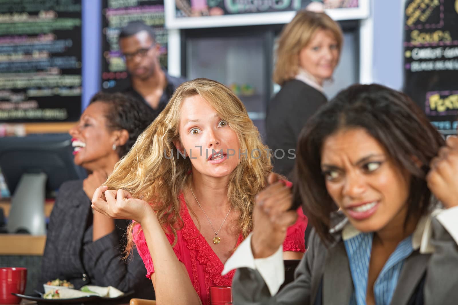 Annoyed business woman next to loud blond woman