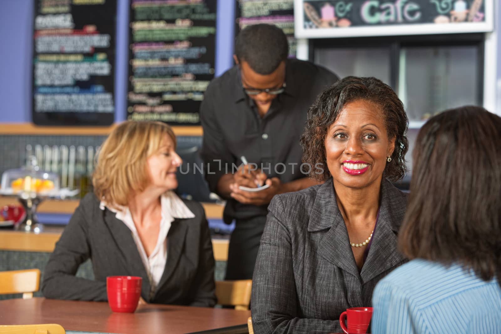 Mature smiling business woman with friend in cafe