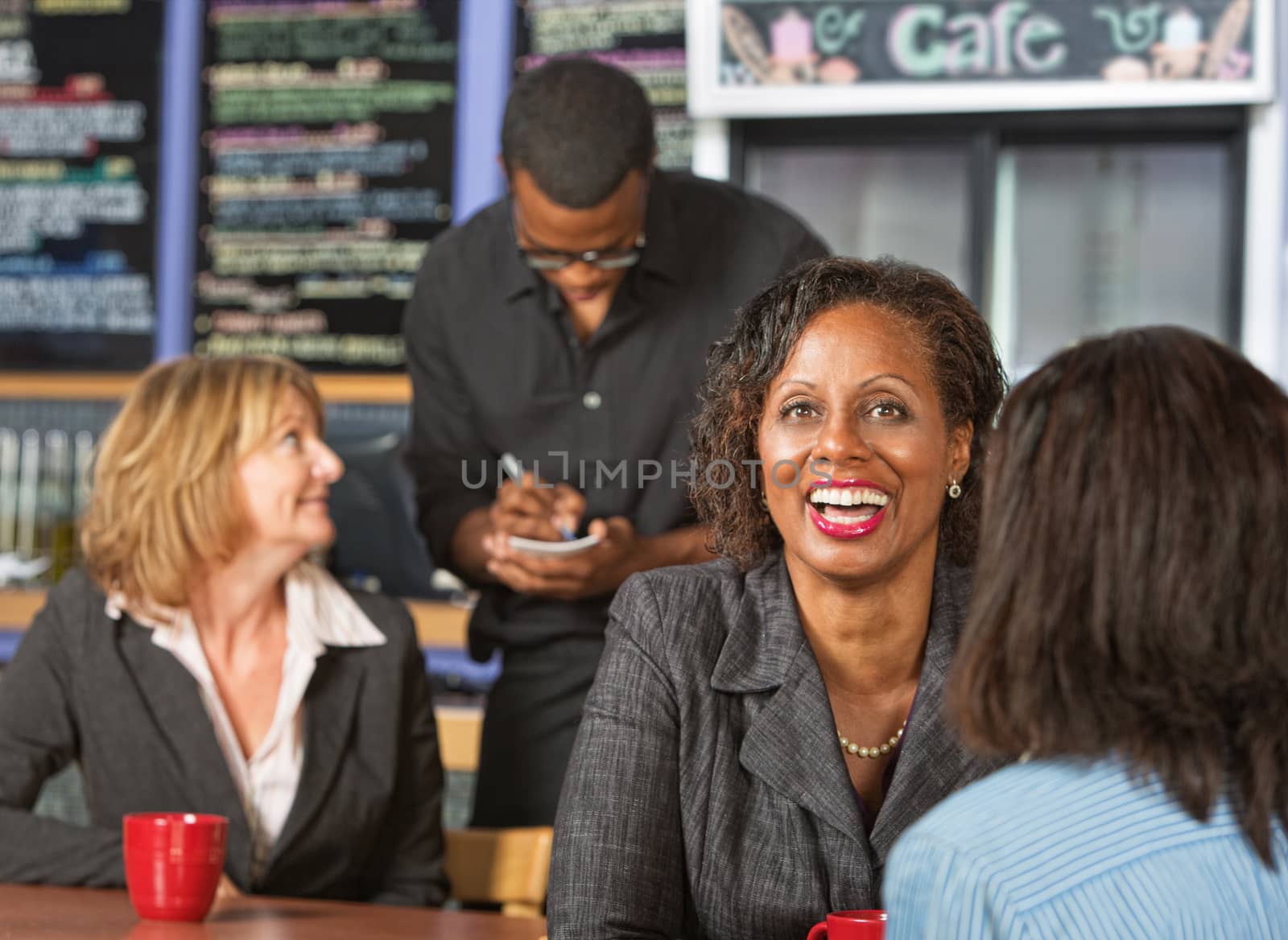 Cute laughing mature business woman with friend in cafe