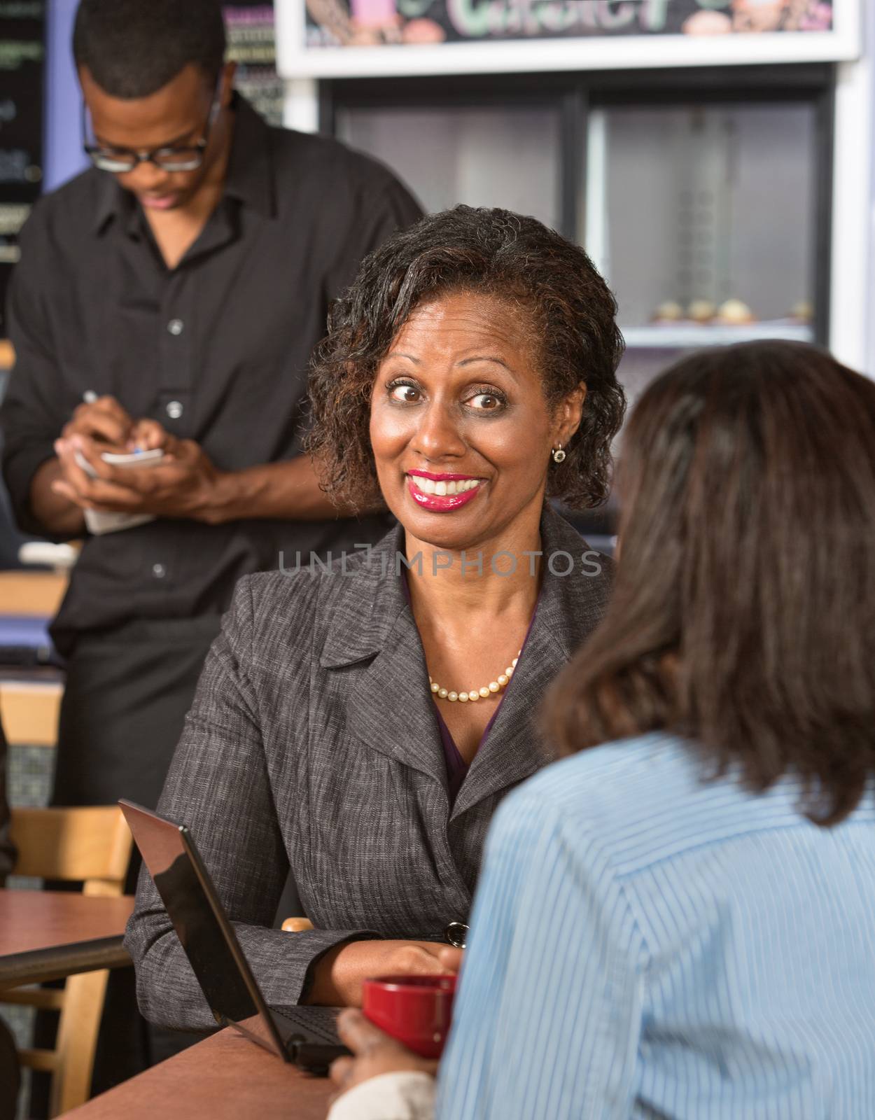 Happy Black business woman with friend in restaurant