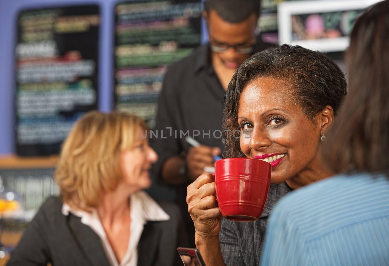 Cheerful business woman sipping beverage in cafe