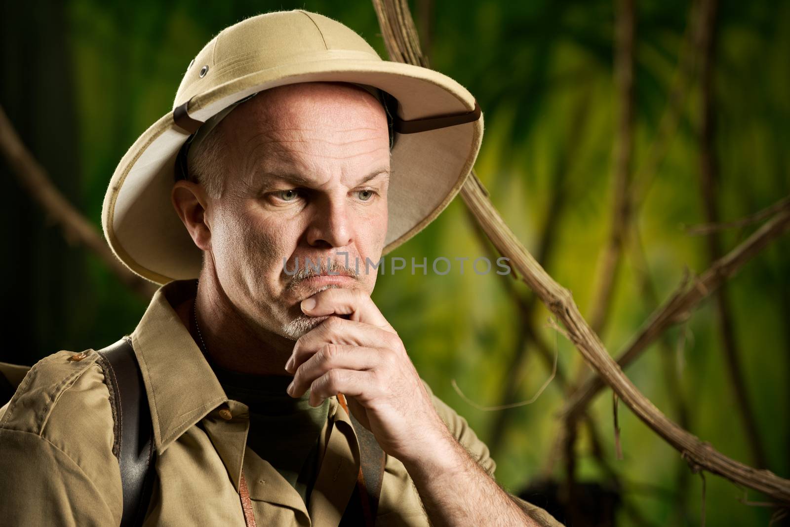 Retro adventurer in the jungle thinking with hand on chin.