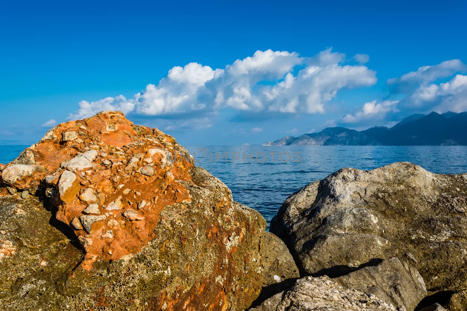 Day photo of Rocks, sea and blue sky with clouds