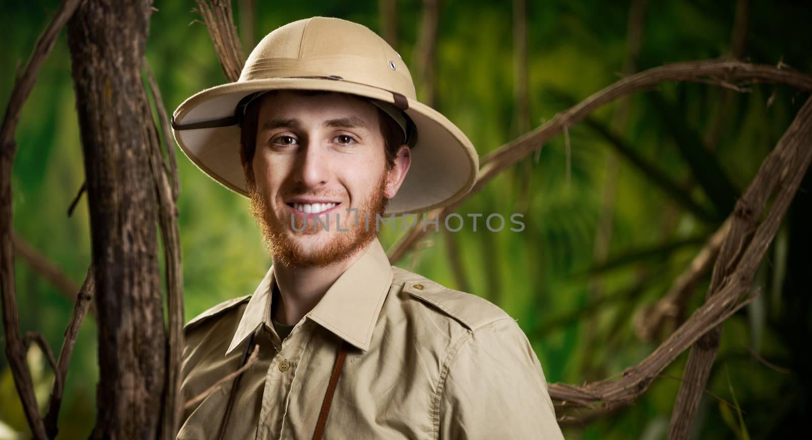 Young confident explorer in the jungle with pith hat smiling at camera.