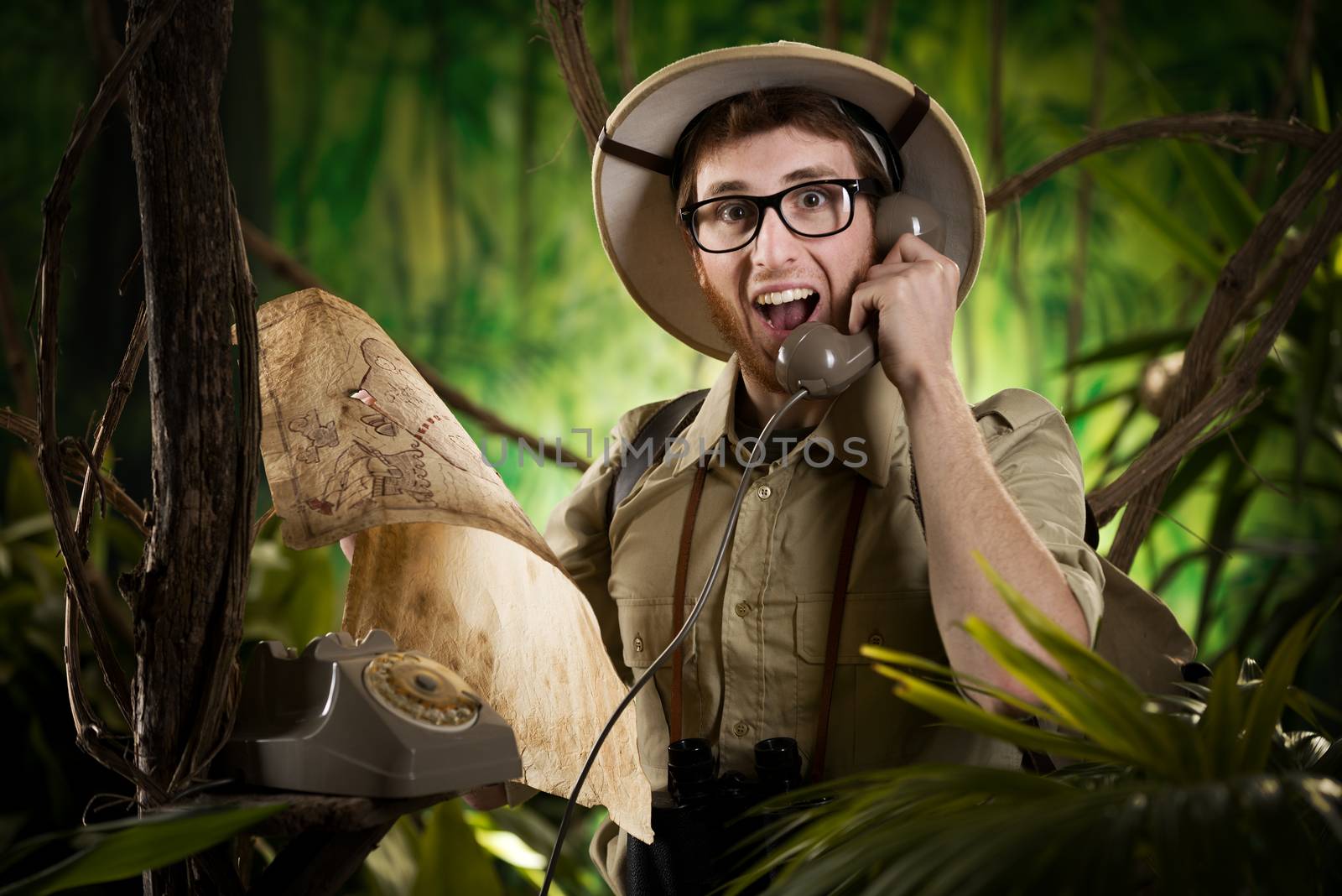 Young retro explorer asking informations in the jungle with vintage telephone and map.