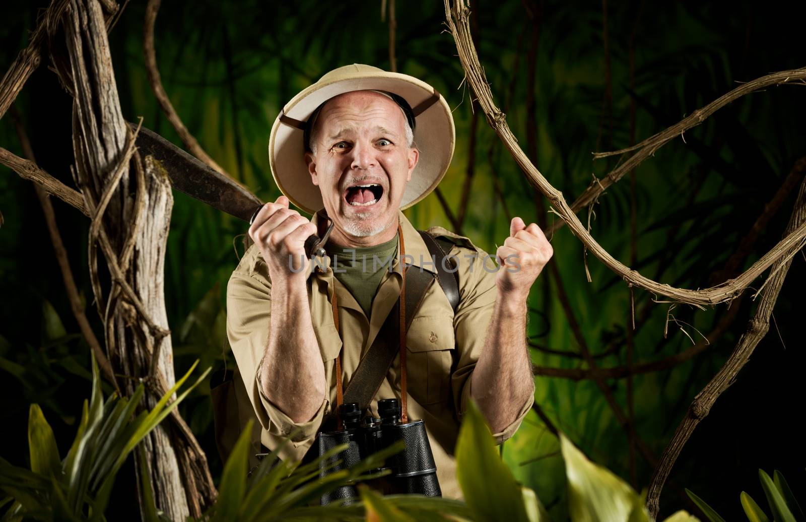 Terrified explorer lost at night in the forest screaming and holding a machete.